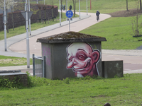 907099 Afbeelding van een graffitikop op een schakelkastje bij de Groenewoudsedijk te Utrecht. Met op de achtergrond ...